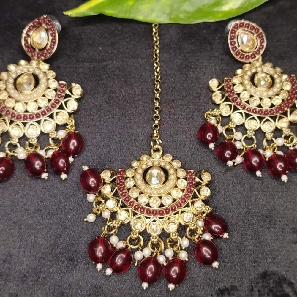 Earrinhs and Maati with Kundan and Maroon Beads on a Black Backgroudn