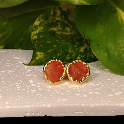 Natural Red Stone Earrings with Golden border on a Textured Wite Surface