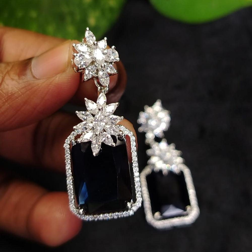 Diamond Replica Earrings with bluestones held by a hand against a dark background