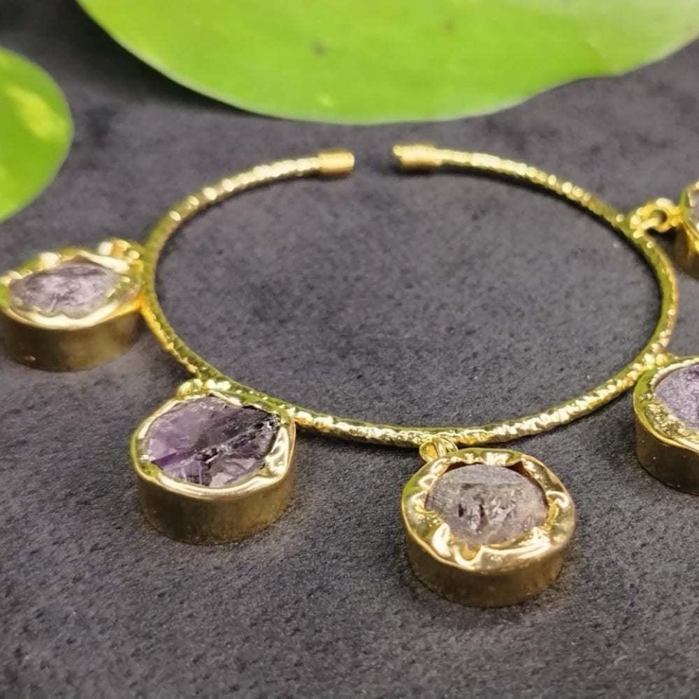 Golden bracelet with Amethyst gemstones on a dark surface