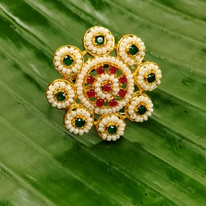 Decorative Ring with gold, green, and red elements on a green leaf background