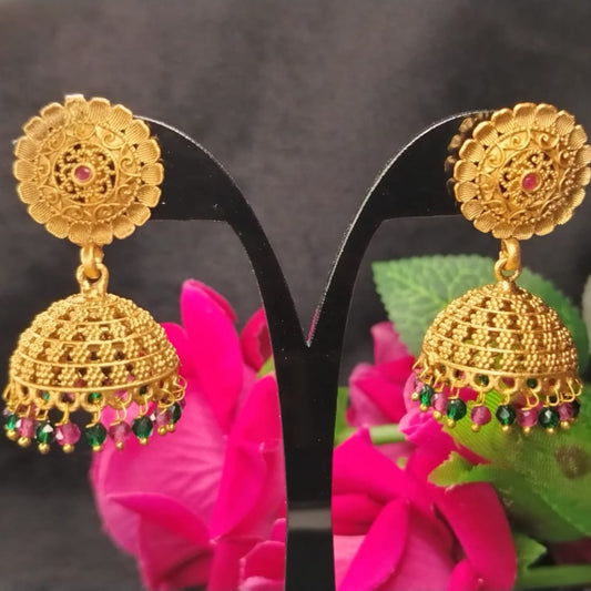 Golden Earrings with colorful beads on a black stand with pink roses and green leaves in the background