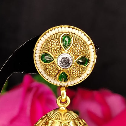 Gold earring with green gemstones and whhite beads on a black background