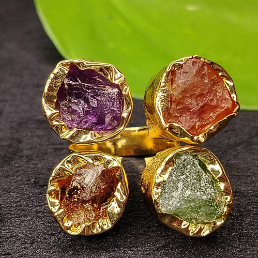 Gold-framed gemstones on a dark surface with a green leaf background