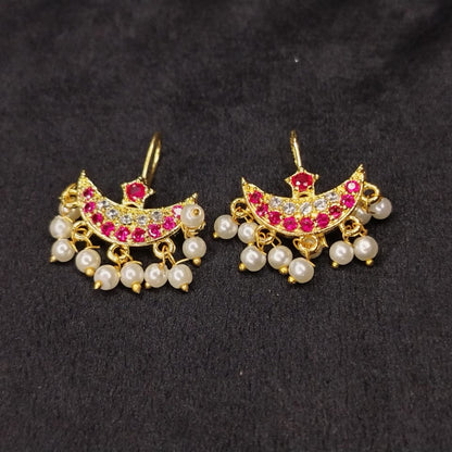 Pair of gold earrings with pearls and red stones on a black background