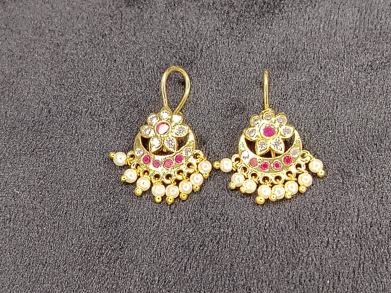 Pair of gold earrings with gemstones on a gray background