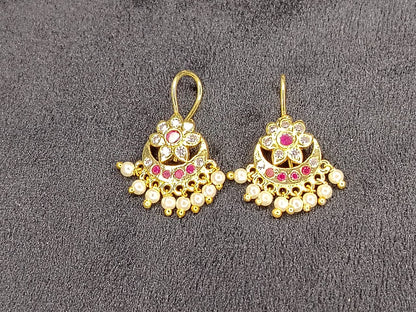 Pair of gold earrings with gemstones on a gray background