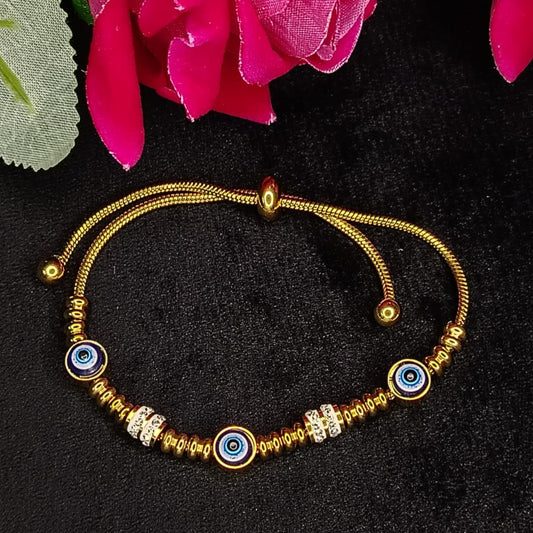 Gold bracelet with blue evil eye beads on a black background