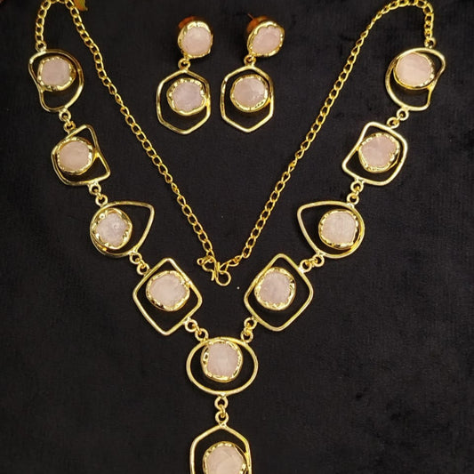 Gold necklace with Rose Quartz and earrings set on a dark background