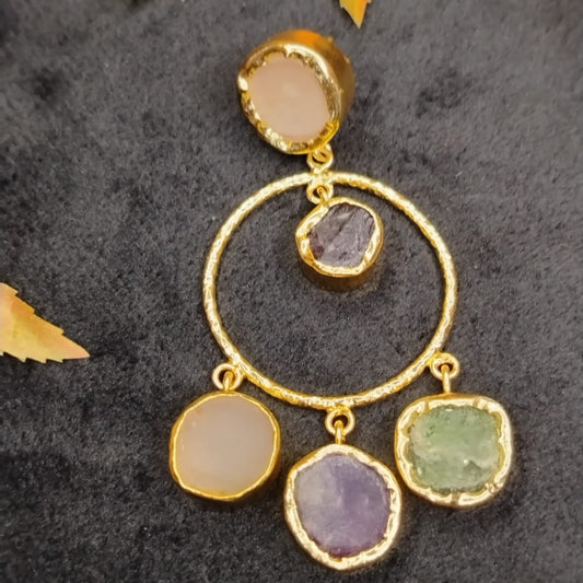 Golden hoop earring with colorful gemstones on a dark textured background 