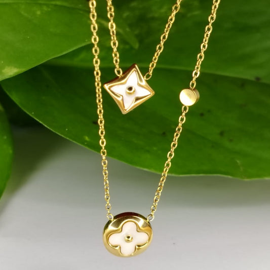 Gold necklaces with star and clover pendants on a green leaf background