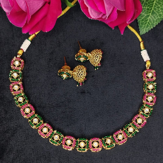 Jewelry set with necklace and earrings on a dark background with pink flowers.