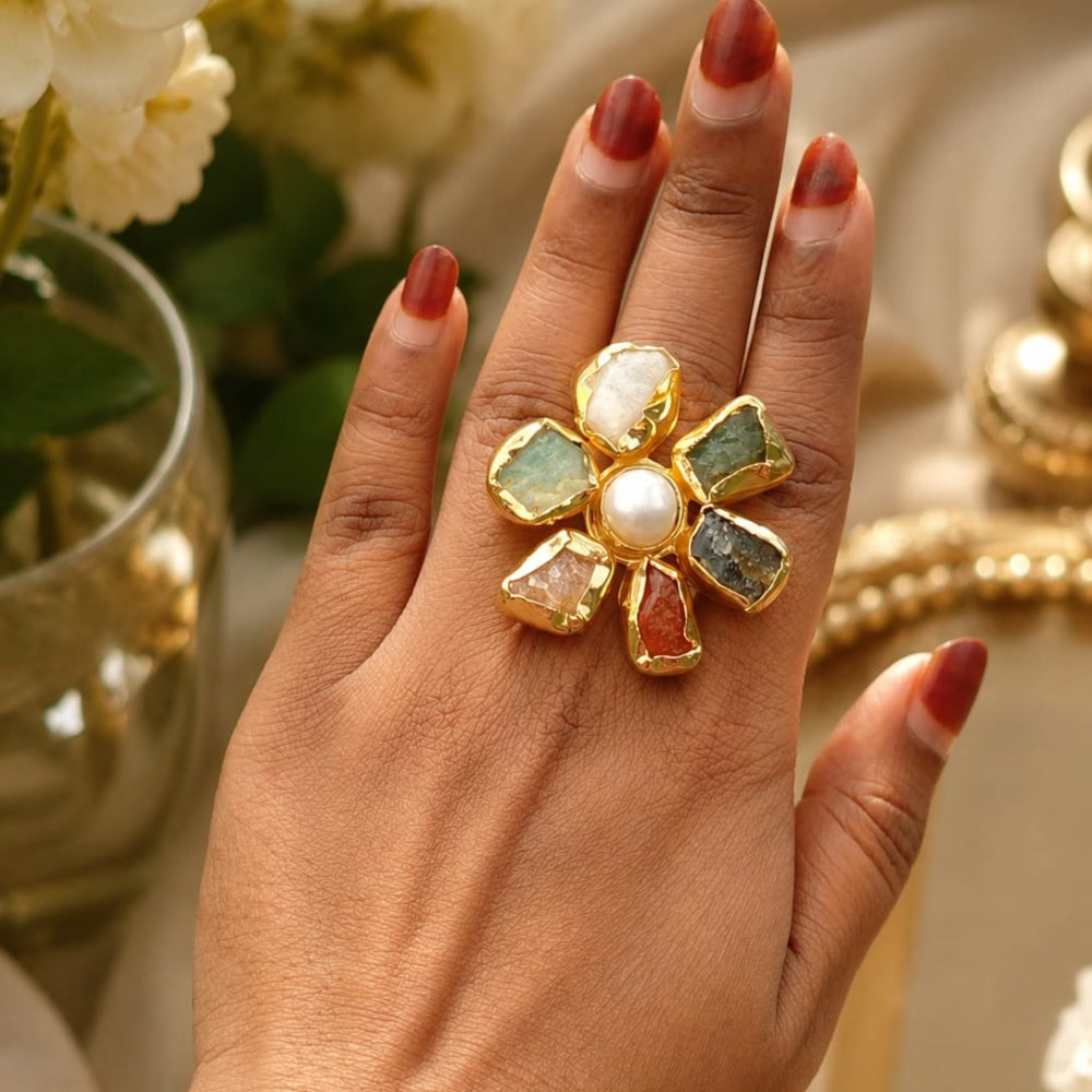 Hand wearing a gold ring with gemstones in a decorative setting