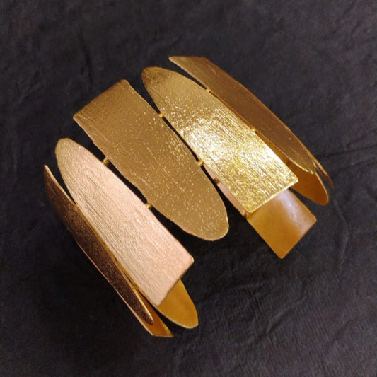 Golden Handcuff Bracelet with a Textured Design on a Dark Background