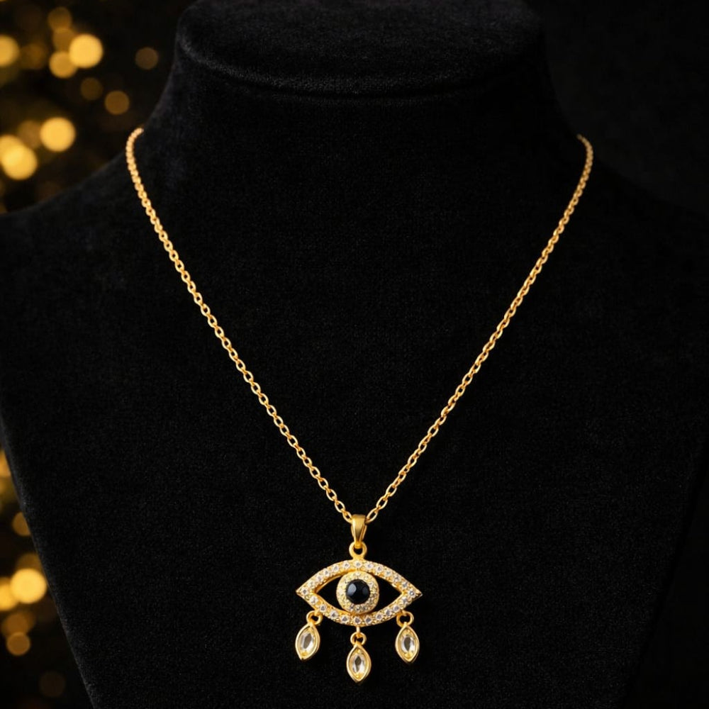 Golden necklace with an evil-eye pendant on a black velvet stand against a dark background.