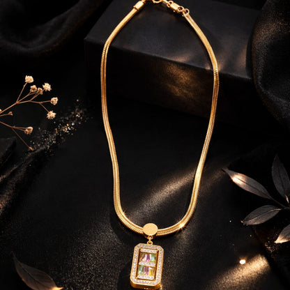 Golden necklace with a rectangular pendant on a dark surface